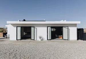 A minimalist, modern residential exterior featuring concrete and glass