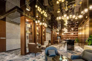 Modern hotel lobby featuring leather furniture, metallic walls, and a marble floor.