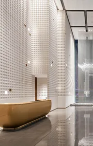 Modern hotel lobby with glass walls, concrete floor, and metallic accents.