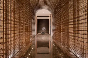A modern hotel lobby featuring a metal grid wall with a tree sculpture in the center.
