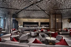 A modern hotel lounge area with metallic texture ceiling and fabric seating.