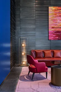 Modern living room featuring a red accent chair, metal floor lamp, and a contemporary painting on the wall.