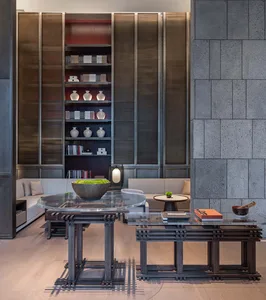 A modern living room featuring wooden furniture, concrete walls, and glass tables
