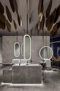 Modern restroom interior with marble countertops, concrete sinks, and illuminated mirrors.
