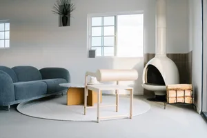 A modern minimalist living room with a blue sofa, round coffee table, and white fireplace.