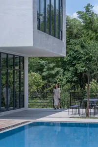 A modern residential home featuring a white concrete exterior and large glass windows.