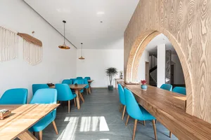 A cafe interior with wooden counters and blue plastic chairs.