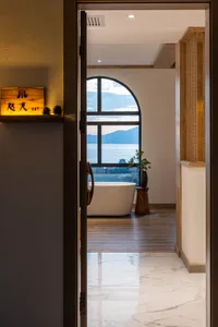 Modern industrial-style bathroom with concrete walls, floor tiles, and a large window overlooking a scenic view of mountains 