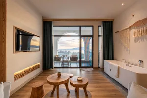A modern minimalist living room with wooden furniture, glass windows, and fabric accents.