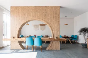 A modern minimalist restaurant interior with wooden furniture and blue chairs.