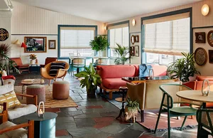 A retro-style living room featuring a wooden floor, fabric furniture, and stone tiles on the wall.