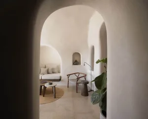 A minimalist living room with concrete walls, a circular coffee table, and a plant.