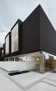 A black modern building with large windows and a white base.
