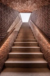 Indoor staircase with brick walls and a skylight at the top.