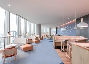 Modern hotel bar with concrete walls, lighting fixtures, and seating areas.