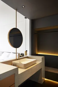 Modern minimalist bathroom featuring a concrete sink and brass accents under a ceiling light