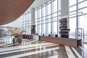 A modern hotel lobby featuring glass, wood, and marble materials.