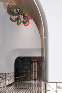 簡約大廳採用大理石地板與牆面，搭配現代拱門與懸掛的彩色玻璃雕塑