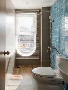 A bathroom interior featuring blue tiles on the walls and concrete floor.