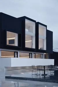 A modern house with large glass windows and a black exterior.