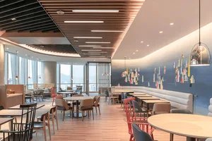 A modern cafe interior with wooden flooring, metallic pendant lights, and upholstered seating.