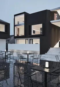 Modern coffee shop exterior with black metal chairs, white metal tables, and glass and metal floors.