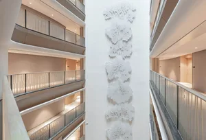 White concrete wall with intricate patterns in a modern interior corridor with balconies.