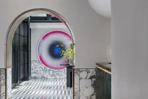 Architectural entrance with modern design featuring marble, concrete, and glass patterns under a large circular artwork.