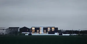 A modern house with a concrete exterior, featuring large windows and a white roof.