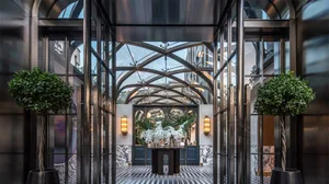 Modern hotel lobby featuring glass walls, marble flooring, and concrete columns.