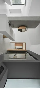 A modern interior space with a minimalist design, featuring concrete walls and a glass floor.
