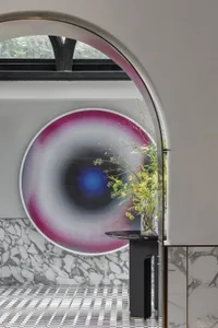 Modern interior space with a large, round glass window featuring colorful abstract art.