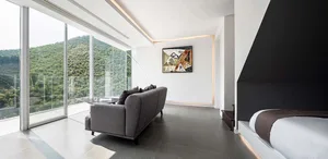 A modern living room with a large glass wall overlooking a scenic landscape.