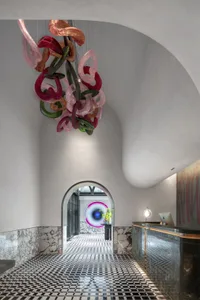 Modern hotel lobby with colorful glass sculpture, marble accents, and black and white checkered floor.