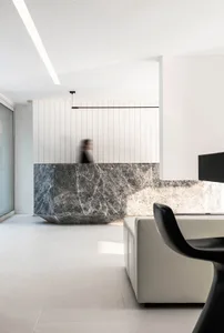 A modern lobby featuring a large marble reception desk and white seating area.