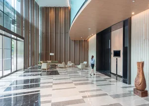A modern office lobby with marble flooring and a wooden elevator control panel.
