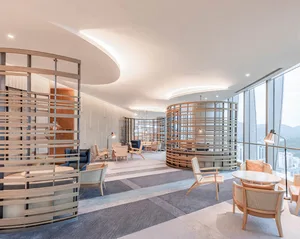 A modern office space featuring wooden furniture and a curved ceiling with integrated lighting.
