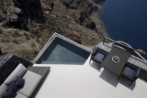 Modern residential pool deck with concrete and stone materials, overlooking the sea.