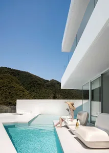 A modern residential home with a concrete poolside and panoramic views of the mountains.