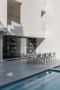 Modern residential exterior design featuring a concrete facade with large windows and a swimming pool.