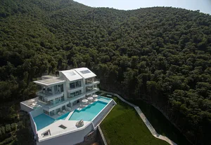 Aerial view of a modern residential pool house with glass and concrete materials.