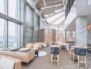 A modern restaurant bar featuring expansive glass windows, concrete structures, and wooden furnishings.