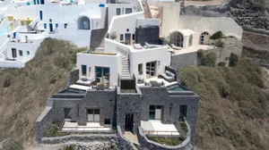 A photograph of a modern building with white stone walls and black accents featuring multiple levels with balconies.