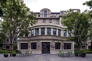 餐廳外觀，石材立面搭配綠色座位區，周圍環繞樹木。
