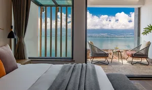 Modern bedroom with a seaview balcony, featuring minimalist furniture and a comfortable bed.