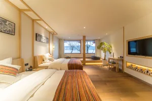 Modern bedroom suite with white bed, glass door, and wooden accents.