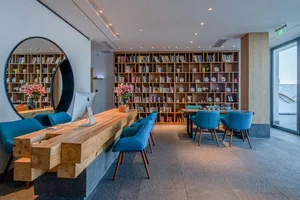 Modern commercial interior with industrial elements, including wooden furniture, floor-to-ceiling shelves, and large windows
