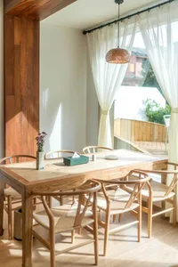 A modern dining room with wooden furniture and a woven pendant light.