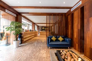 Modern lobby interior features a cozy seating area with a blue couch and wooden walls and floors.