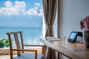 Modern office space with wooden desk, glass window, and ocean view.